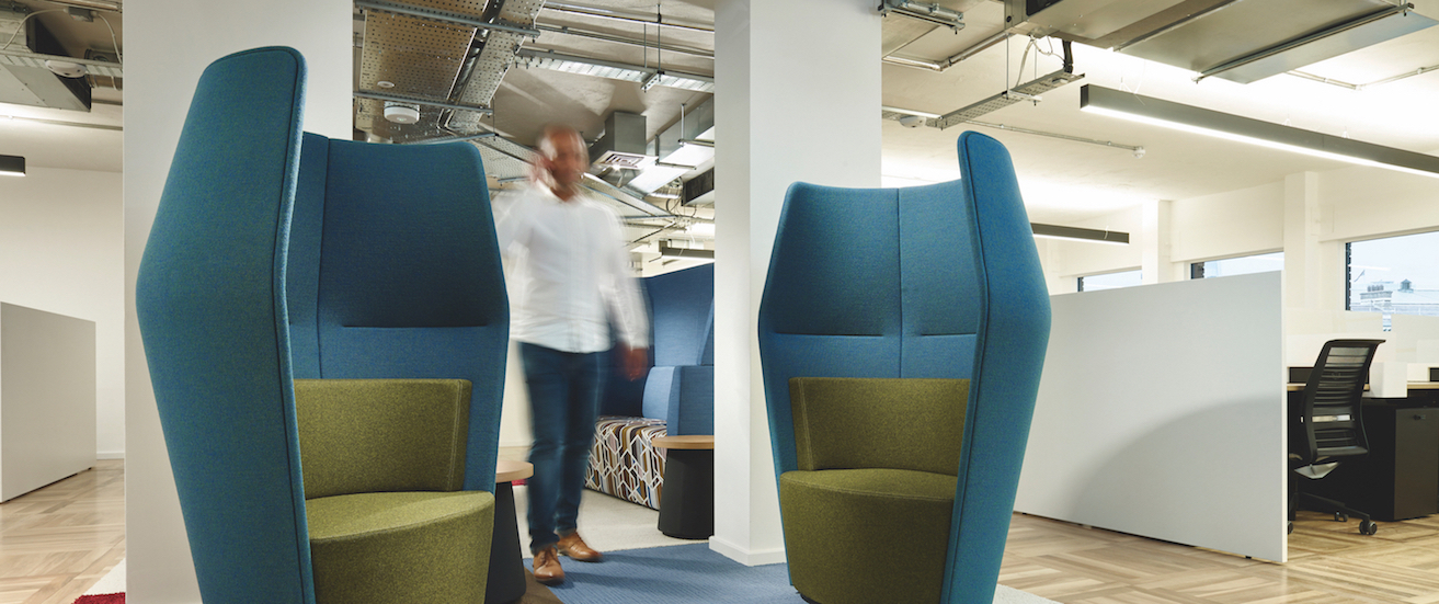 Breakout space in Us&Co's central London office space. Featuring blue comfortable chairs and a fixed desk for rent in the background.